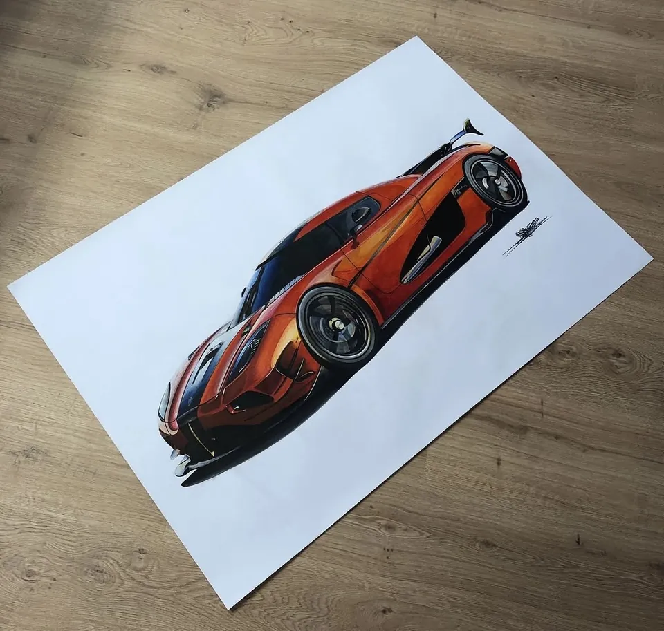 Kresba oranžového Koenigseggu na velkém archu položeném na dřevěné podlaze